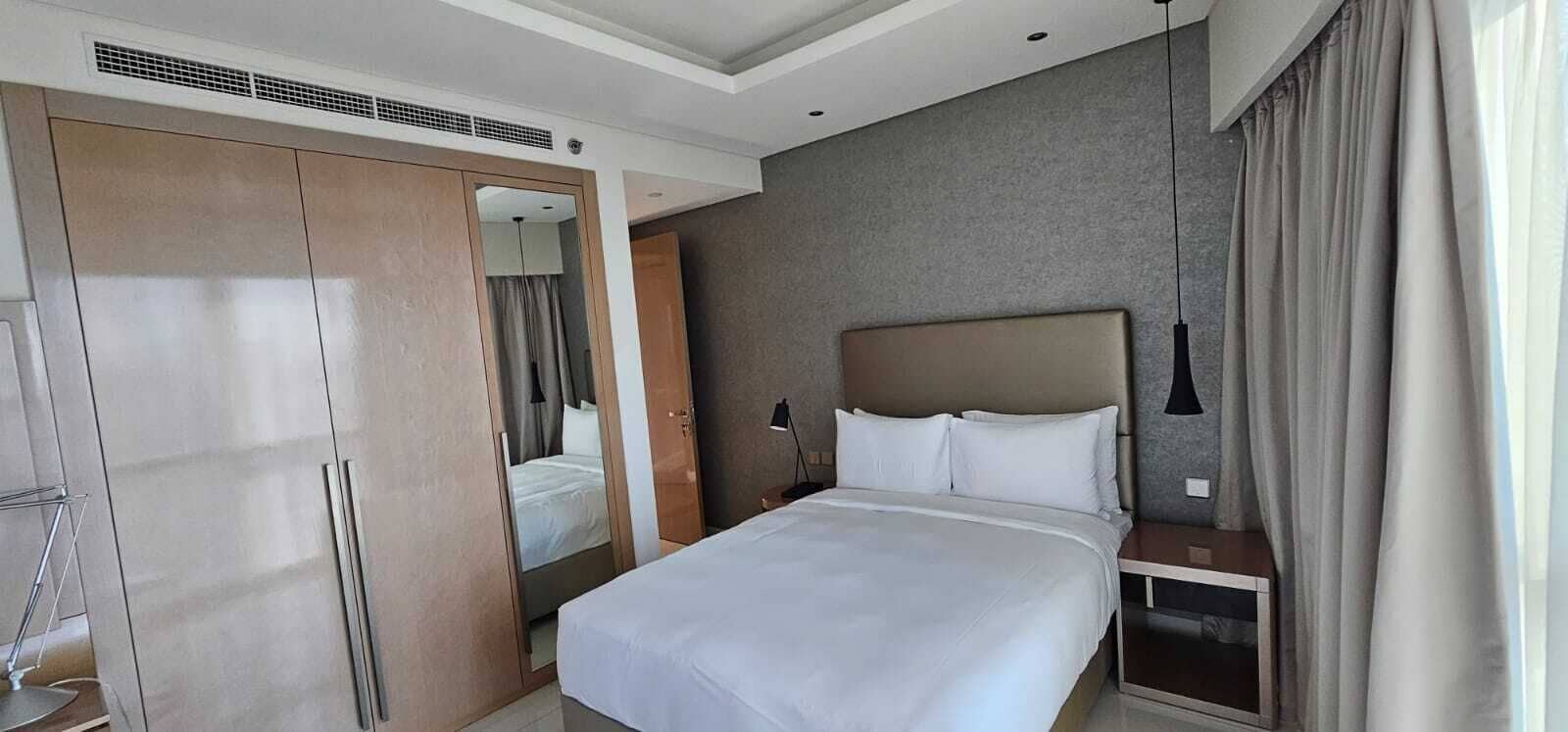A hotel room with a bed, a wardrobe, a bedside table, and a nightstand.