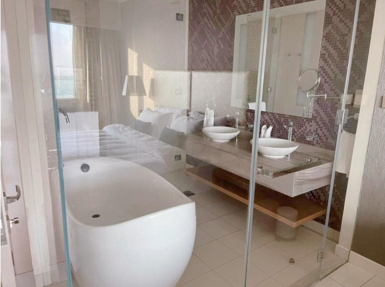 Un baño moderno con ducha envuelta en vidrio, una bañera grande y un lavamanos doble.