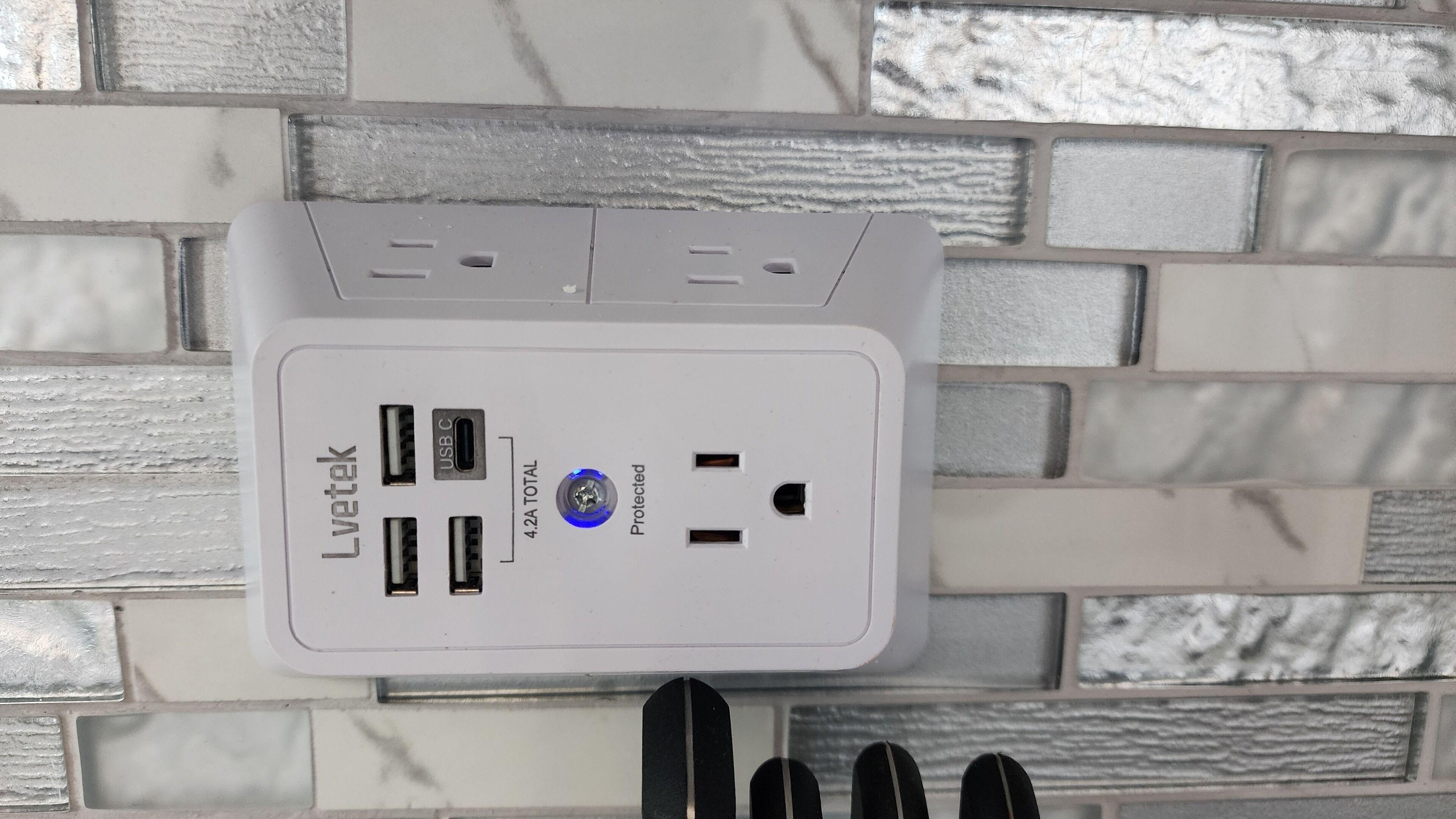 A Lvitotek power strip with multiple USB ports and a total of 4.2A current capacity, mounted on a textured wall.
