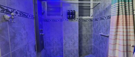 Ein Badezimmer mit Dusche, Handtuchhalter und Ablage für Toilettenartikel.