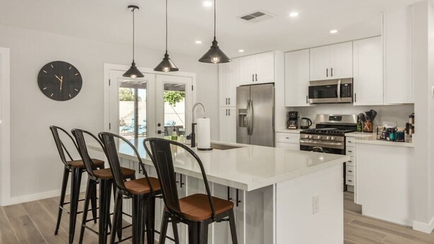 A modern kitchen with white cabinets, stainless steel appliances, and pendant lighting. - 4 Brdm / 6 Beds / Pool / PetsOK / Fenced Yard (Scottsdale)
