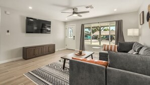A modern living room with a flat-screen TV, grey sofa, patterned rug, and a ceiling fan. - 4 Brdm / 6 Beds / Pool / PetsOK / Fenced Yard (Scottsdale)