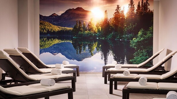 Une salle de spa équipée de fauteuils inclinables, de serviettes et d’une grande fresque murale représentant un paysage de lac et de montagnes.