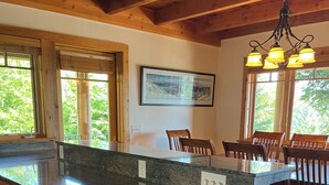 Une cuisine dotée de meubles en bois, de plans de travail en granit et d’un coin repas avec des chaises en bois.
