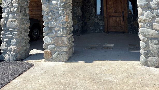 Un arc en pierre menant à une porte en bois, faisant partie d’un bâtiment doté d’un balcon et de murs en pierre.