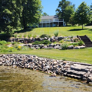 A landscaped garden with a pond, stone steps, and a house in the background. - Lake Latoka Home w/Paddle boards, Kayaks, Paddle Boat, Pool Table, Dock, Sunsets (Alexandria)