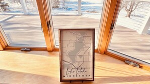 A framed map of Lake Atoka, Minnesota, on a wooden surface by a window with a view of a snowy landscape.