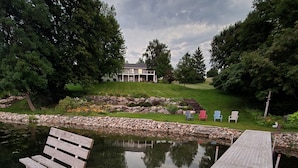 A wooden deck with a bench and a small pond, surrounded by a stone wall and greenery.