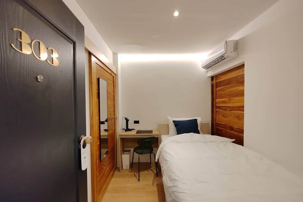 A compact hotel room with a bed, a desk, and a chair.