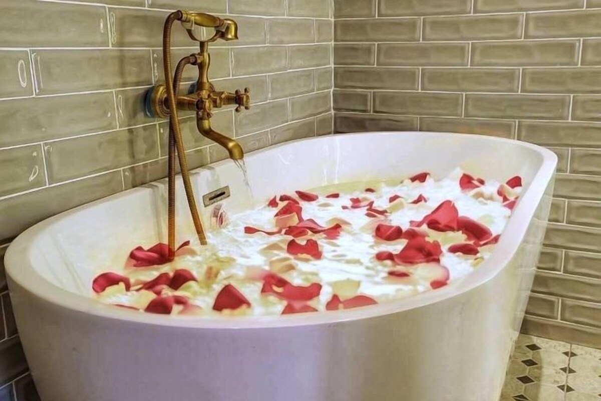 Una bañera llena de agua y pétalos de rosa.