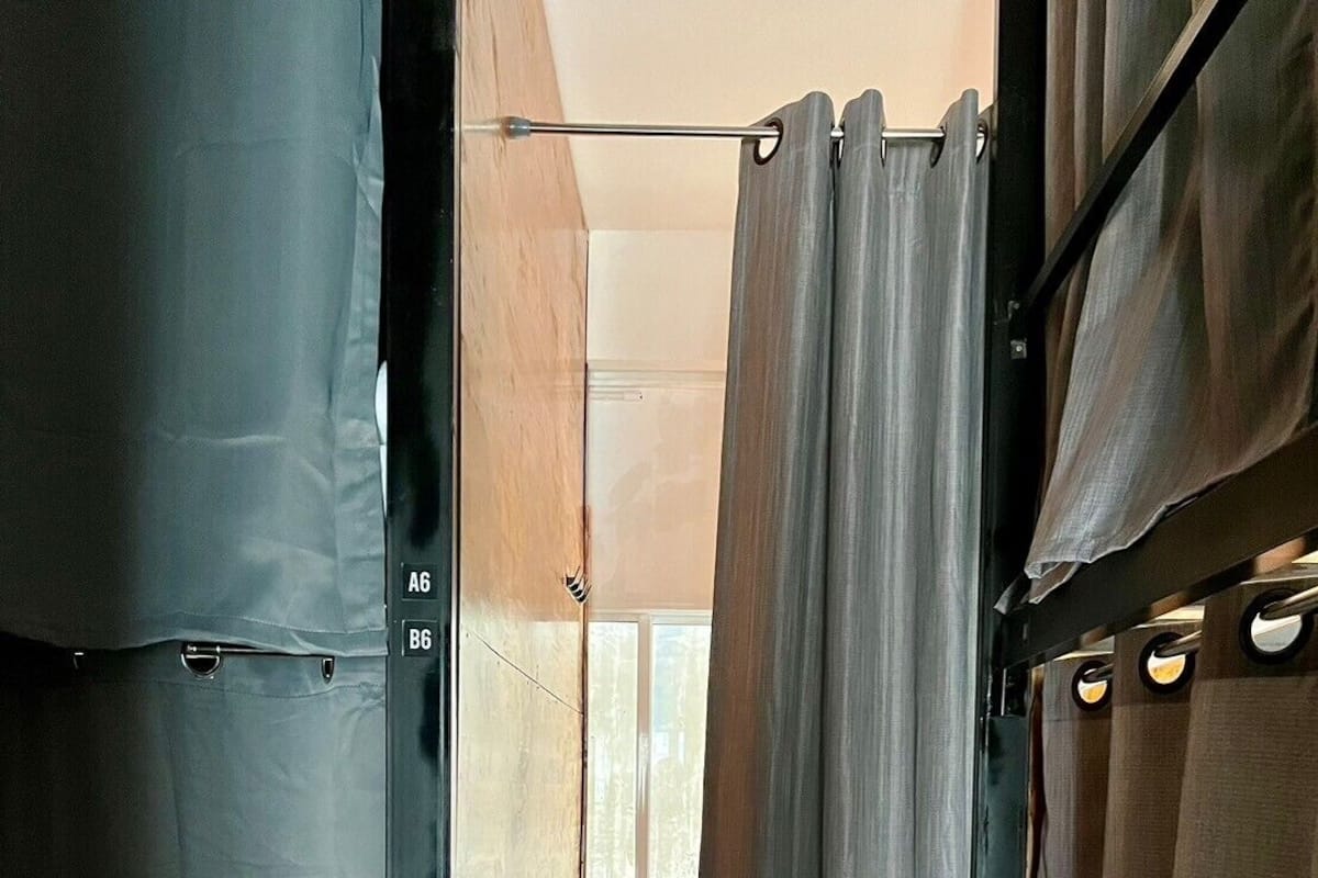 A narrow, enclosed space with a bunk bed, a small window, and a metal grate at the bottom.