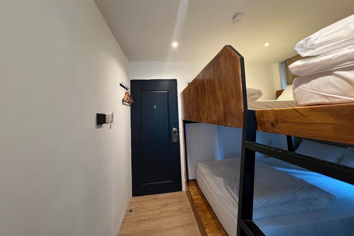 A compact room with a bunk bed, a door, and a small wall-mounted light fixture.