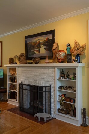 A fireplace with a white brick surround, flanked by shelves with various decorative items.