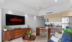 Una sala de estar moderna con un televisor de pantalla plana, muebles de madera y un ventilador de techo.