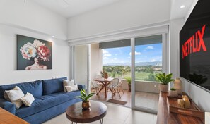 A modern living room with a blue sofa, a coffee table, and a painting on the wall. - Altamar: Penthouse Near Beach with Gym & Pool (Nuevo Nayarit)