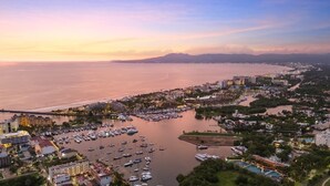 An aerial view of a coastal city with a marina, hotels, and a river.
