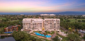 A multi-story hotel with a swimming pool and a golf course in the background. - Altamar: Penthouse Near Beach with Gym & Pool (Nuevo Nayarit)