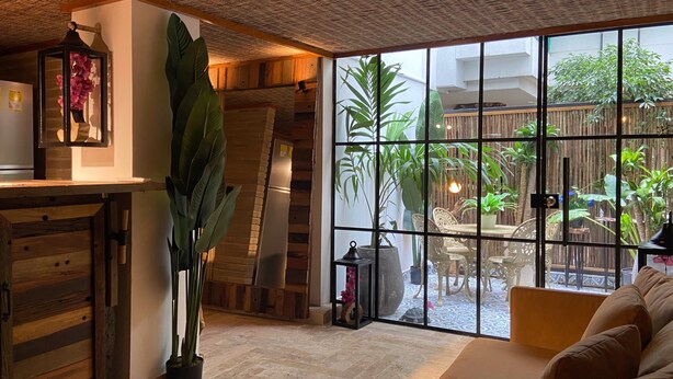 Ein gemütliches Wohnzimmer mit großem Fenster, Holzbalkendecke und einer bequemen Couch.