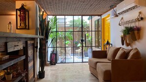 Ein gemütliches Wohnzimmer mit großem Fenster, einer Couch, einem Couchtisch und einem Bücherregal.
