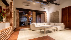 Un amplio salón con un sofá blanco, una mesita de centro y una pared decorada con ladrillo.