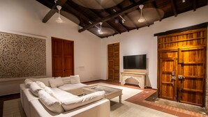 Una sala de estar moderna con un sofá seccional, una chimenea, puertas de madera y un televisor grande.