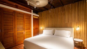 Un dormitorio con una cama grande, un armario de madera y una mesita redonda.