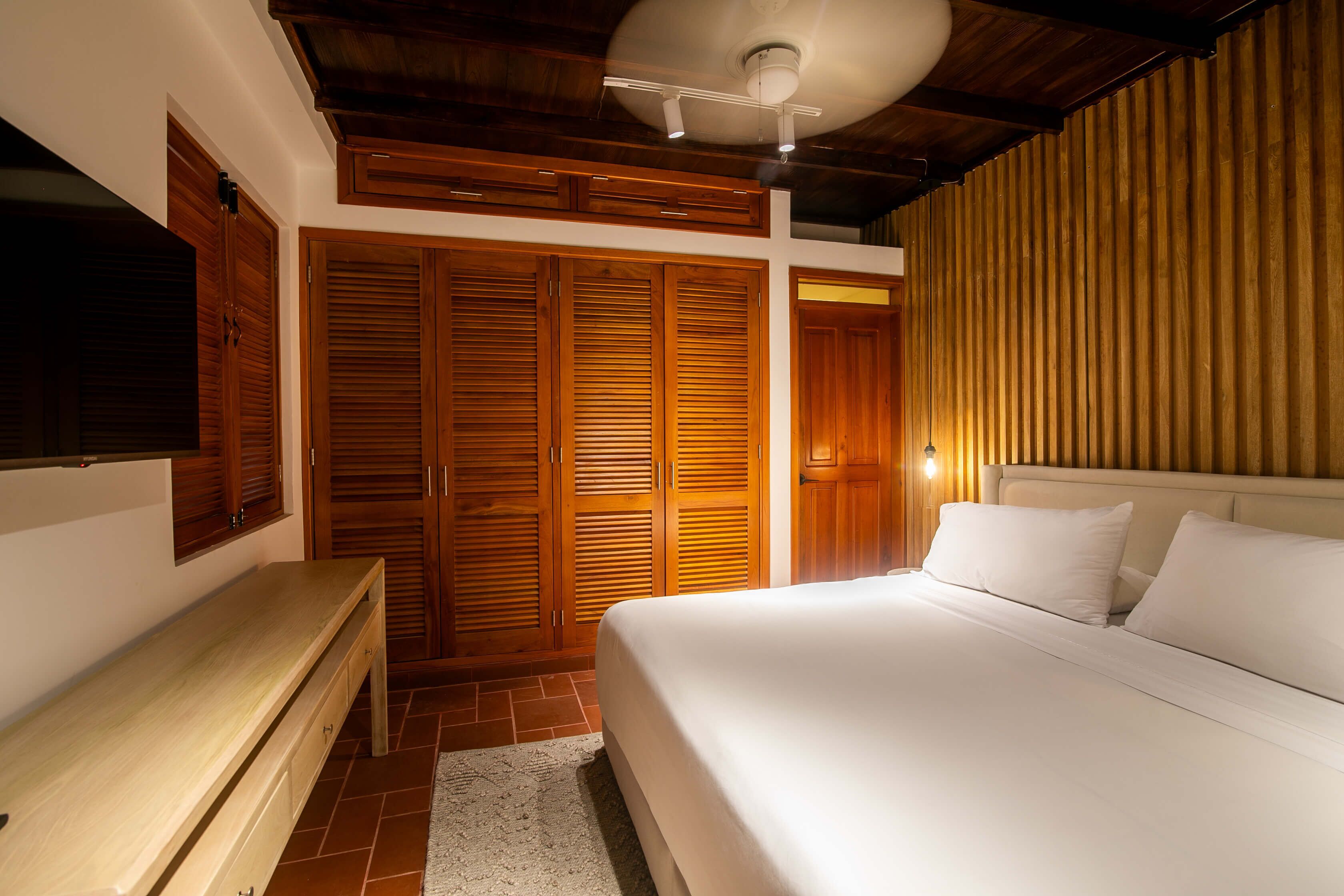 Un dormitorio con cama, armario de madera y un banco.