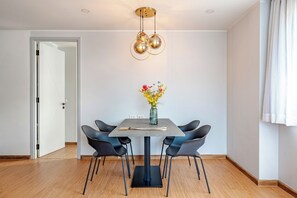 A dining area with a table, chairs, a vase with flowers, and a pendant light. - Modern 61m² Apt - Central Chalong/ Fast WiFi (Phuket)