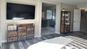 A bedroom with a large TV, wooden dresser, and a ceiling fan. - Remodeled 3 bedroom house in Mesa w/heated pool and golf course views (Mesa)