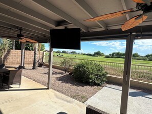 A covered patio area with a view of a golf course, outdoor furniture, and a speaker mounted on a pole. - 3 bedroom house in Mesa w/heated pool and golf course views (Mesa)