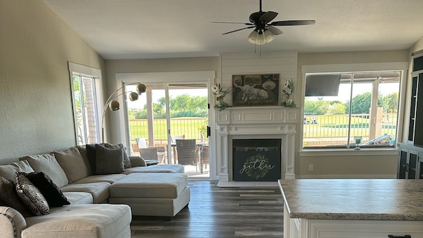 A spacious living room with a sofa, a fireplace, and a view of a backyard. - Remodeled 3 bedroom house in Mesa w/heated pool and golf course views (Mesa)