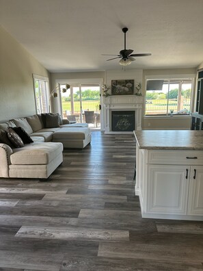 A spacious living room with a sofa, a fireplace, and a view of a backyard. - 3 bedroom house in Mesa w/heated pool and golf course views (Mesa)