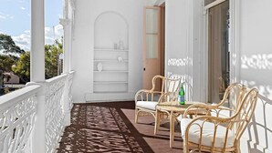 A balcony with white railings, wicker furniture, and a built-in shelf unit. - Fitzroy Private Rooms @ 132 Nicholson Homestay (Fitzroy)