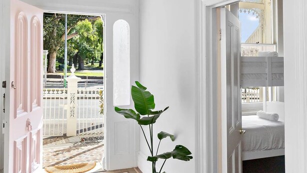 A hallway with a geometric patterned rug, a potted plant, and a wicker pendant light. - Fitzroy Private Rooms @ 132 Nicholson Homestay (Fitzroy)