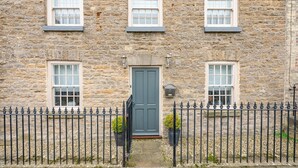 A stone building with three windows, a dark door, and a black iron fence. - Maison Cottage -  a cottage that sleeps 4 guests  in 2 bedrooms (Richmond)