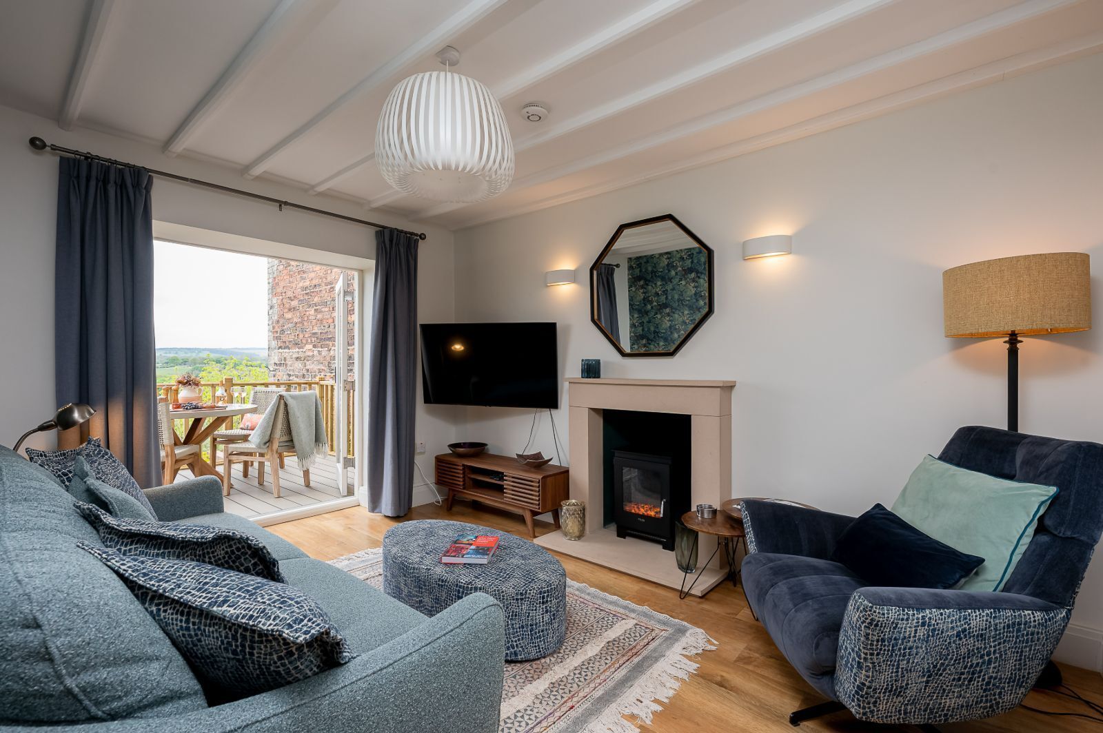 A modern living room with a fireplace, a television, and a balcony with a view.