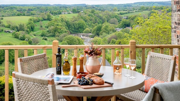 A round table with wicker chairs on a balcony overlooking a lush landscape. - Maison Cottage -  a cottage that sleeps 4 guests  in 2 bedrooms (Richmond)