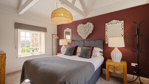 A bedroom with a large bed, a window with a view, a hanging light, and a wall-mounted mirror. - Maison Cottage -  a cottage that sleeps 4 guests  in 2 bedrooms (Richmond)