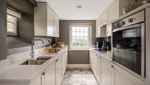 A modern kitchen with a window, stainless steel appliances, and a patterned floor. - Maison Cottage -  a cottage that sleeps 4 guests  in 2 bedrooms (Richmond)