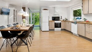 Una cocina moderna con tragaluz, armarios de madera y un comedor con mesa y sillas.