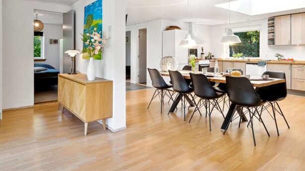 Una cocina moderna con comedor, que incluye una mesa y sillas de madera, iluminación colgante y vistas al exterior.