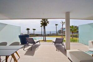 A balcony with a pool view, lounge chairs, and a table. - Happy Travel South Beach 1-1b (Benalmádena)