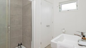 Een badkamer met douche, toilet en wastafel.