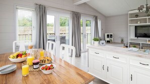 Een keuken met een ontbijt gedekte eettafel, een televisie en uitzicht op de omgeving.