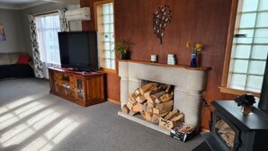 A living room with a fireplace, a television, and a sofa. - Home Sweet Home (Timaru)