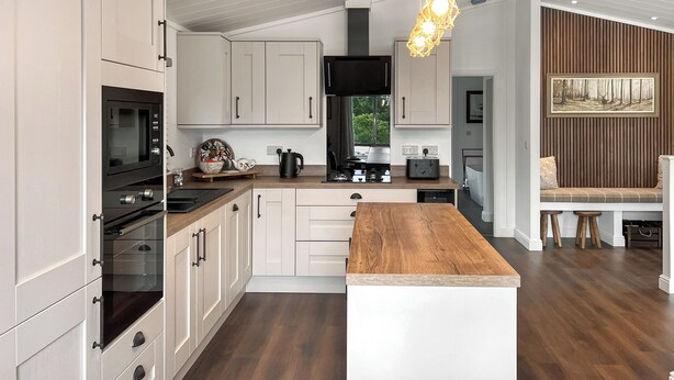 Een moderne keuken met ingebouwde apparatuur, een houten eiland en een hanglamp.