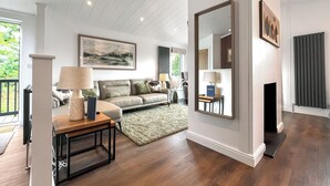 A living room with a sofa, a coffee table, a fireplace, and a large mirror. - Escape to a luxurious one-bedroom lodge designed exclusively for couples. (Chipping)