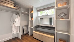 Een inloopkast met planken, een spiegel en een radiator.