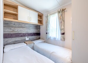 A bedroom with two beds, a wooden headboard, a white wardrobe, and a window with curtains. - Coldstream Retreat - 3 Bedroom (Pet Friendly) (Coldstream)