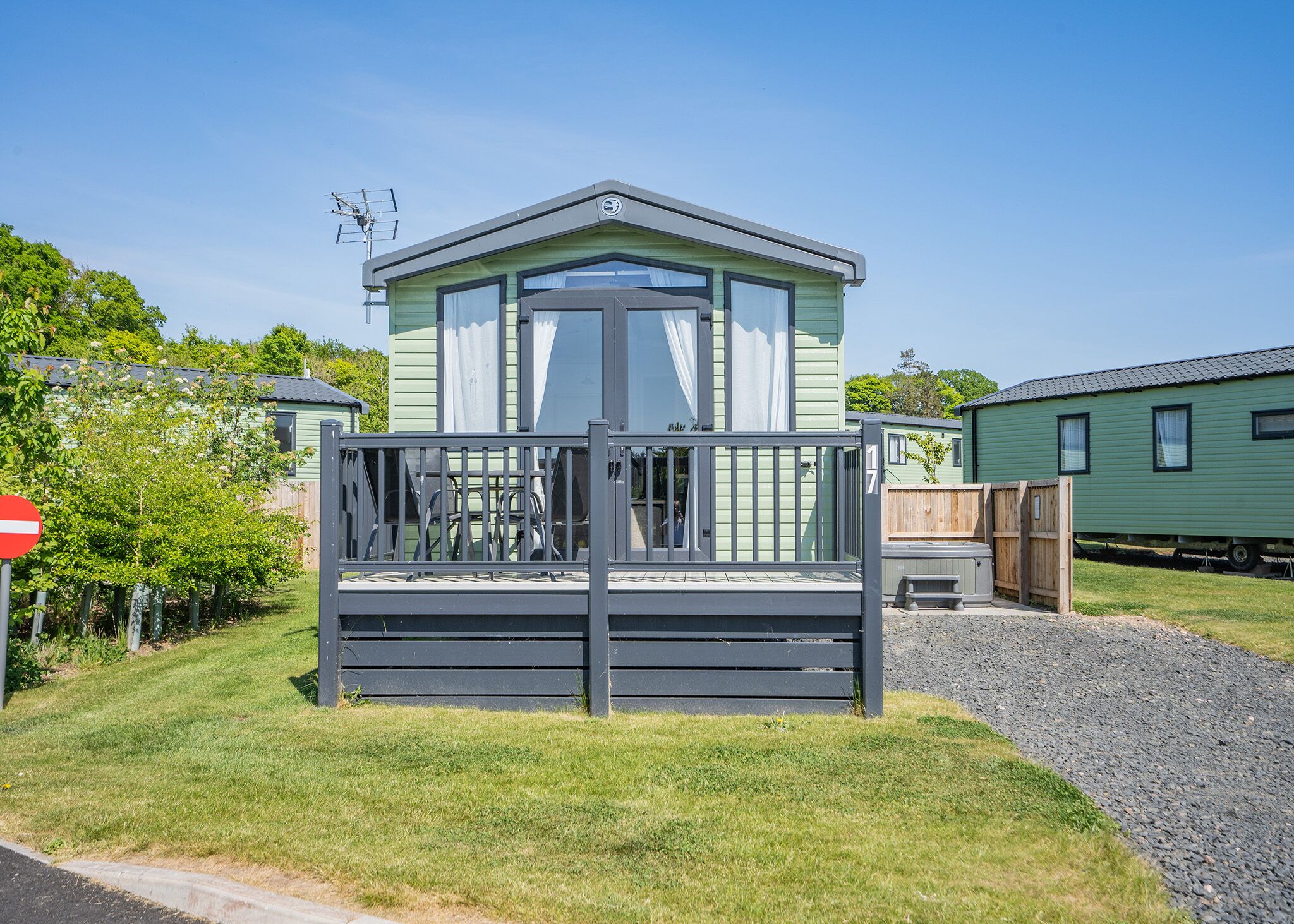 A mobile home with a fenced front yard, a clear sky, and a 'no entry' sign.